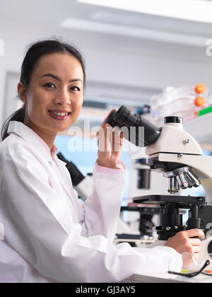 Scienziato visualizzazione di un vetrino di vetro contenente un campione per analisi di laboratorio Foto Stock