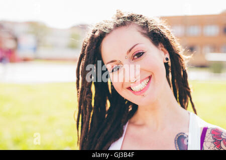 Ritratto di tatuati giovane donna con Dreadlocks nel parco urbano Foto Stock