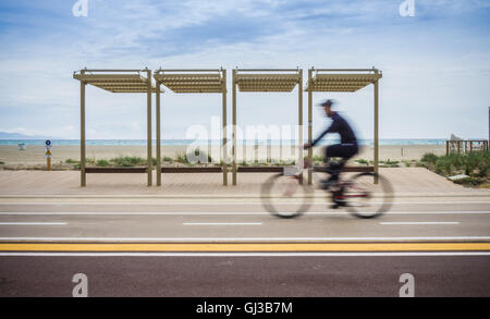 Moto sfocata del ciclista escursioni in bicicletta lungo la strada costiera, Cagliari, Italia Foto Stock