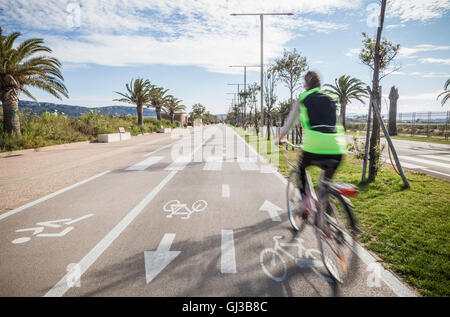 Vista posteriore del ciclista usura alta vis jacket ciclismo in pista ciclabile Foto Stock