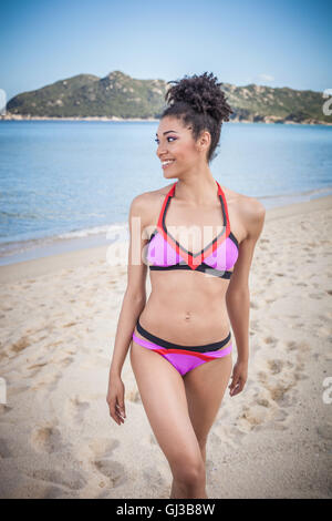 Giovane e bella donna che indossa un bikini rosa permanente sulla spiaggia, Costa Rei, Sardegna, Italia Foto Stock