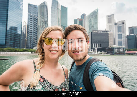 I turisti in posa di fronte dello skyline di Singapore, Marina Bay Foto Stock