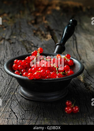 Ribes rosso in piccole vintage del vaglio di metallo, rustico tavolo in legno Foto Stock