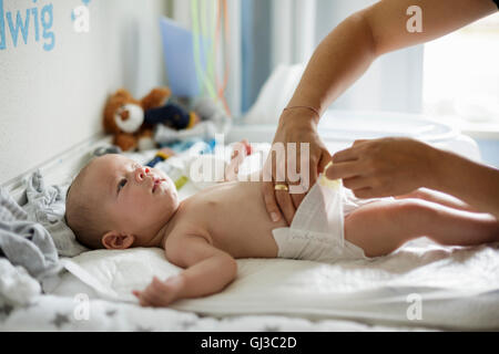 Le madri mano controllando la scioltezza di baby figli pannolino Foto Stock