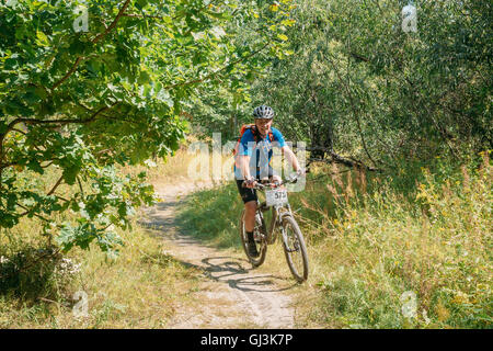 Gomel, Bielorussia - Agosto 9, 2015: ciclista uomo adulto in attrezzature sportive a cavallo in Mountain Bike sulla sabbia di avvolgimento via sentiero in S Foto Stock