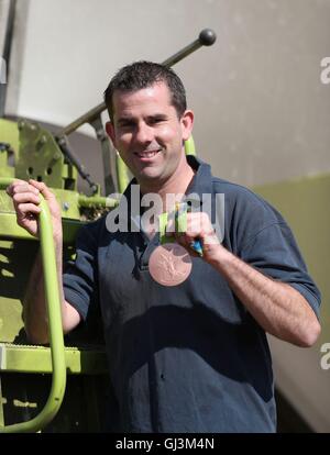 Olympic medallist in bronzo ed Ling pone con la sua medaglia al fianco di una mietitrebbia, dopo ritornò presto dal Brasile per aiutare la sua famiglia con questo anno di raccolto sulla loro fattoria vicino a Wellington, Somerset. Foto Stock