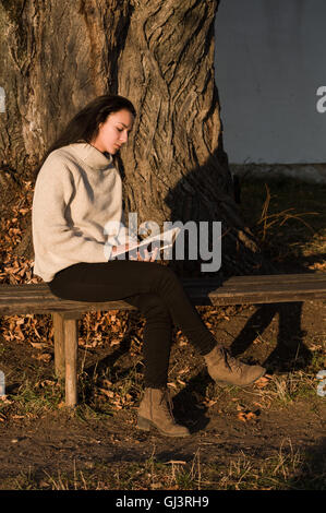 Una ragazza la lettura di un libro in autunno. Foto Stock