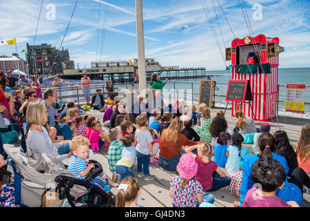 Aberystwyth Wales UK, sabato 13 agosto 2016 UK Meteo: una folla di persone e bambini godendo la visione di un tradizionale Punch e Judy mostrano nel caldo sole estivo al mare annuale a Shore Food festival sul lungomare di Aberystwyth sulla west wales Coast. Dopo un freddo e ventilato in settimana, il meteo è impostato per migliorare nei prossimi giorni, culminante in una mini-canicola martedì, con temperature meteo per raggiungere l'alta 20s o bassa 30s centigradi Photo credit: Keith Morris/Alamy Live News Foto Stock