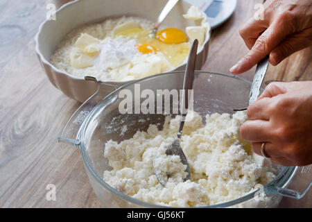 Uova di miscelazione di farina per torte e il burro in una ciotola di ceramica per la preparazione di una torta di pan di spagna Foto Stock