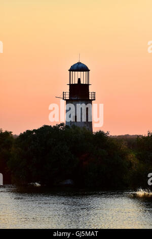 Abbandonato il vecchio e stagionato faro al tramonto sulle rive di un fiume Foto Stock