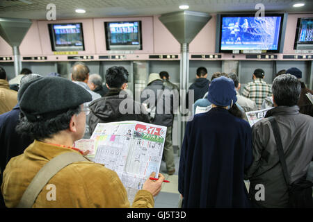 All'interno dell'immenso stand gli scommettitori di controllo della forma di cavalli di razza 11, la grande gara della giornata la American Jockey Club con coppa a Foto Stock