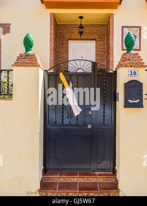 Una baguette che era stato consegnato fresco per una casa è appeso dal fronte cancello di ingresso mantenuto in posizione da un sacchetto di plastica. Foto Stock