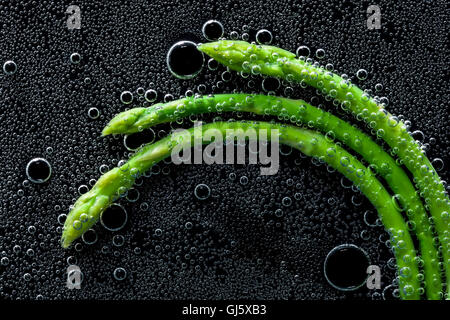 Asparagi, erba in acqua minerale, una serie di foto. Close-up di acqua gassata su sfondo nero Foto Stock