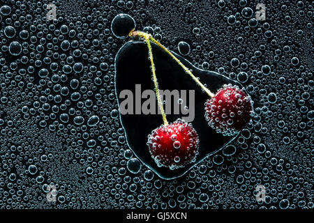 Cherry Berry in acqua minerale, una serie di foto. Close-up di acqua gassata su sfondo nero Foto Stock
