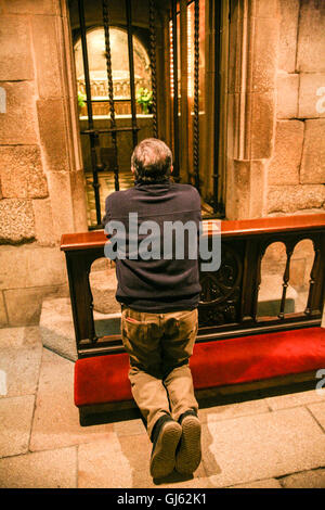 Pregando sotto l'altare della Cattedrale di Santiago di Compostela, qui nella cripta che contiene una teca in argento che contiene ripetutamente il corpo/resta/le reliquie di San Giacomo il Grande, uno degli apostoli di Gesù Cristo e il santo patrono della Spagna. Migliaia di visitatori e pellegrini si raccolgono in Santiago de Compostela per celebrare il St James Day. 25 luglio è St James Day, il santo patrono della Spagna. La cattedrale è la famosa meta di pellegrinaggi in tutta Europa, il Camino de Santiago, a questo spot in Galizia nel nord ovest della Spagna. Foto Stock