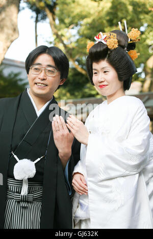 Qui la sposa e lo sposo mostrano le loro fedi per un fotografo. In un tradizionale giapponese Shinto cerimonia di nozze anelli ar Foto Stock