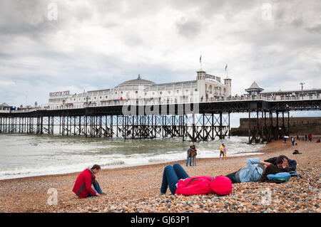 Persone che prendono il sole in giacche sulla spiaggia di Kemptown Brighton vicino al molo di Brighton in una fredda giornata estiva a Brighton, Essex orientale, Regno Unito a partire dal 2012 Foto Stock