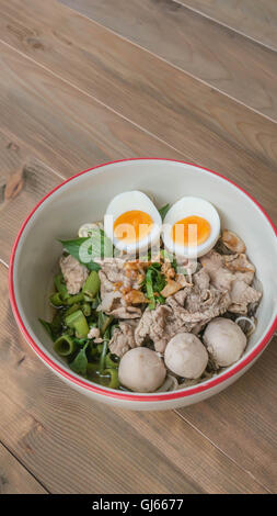 Bianco asiatici tagliatelle con carne di maiale e le verdure in coppa sopra lo sfondo di legno Foto Stock