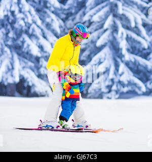 La madre e il bambino a sciare nelle alpi. Active mamma e bimbo capretto con casco, occhiali e poli. Foto Stock