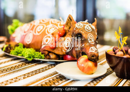 Decorate e maialino da latte arrosto con un Apple nella sua bocca su una piastra bianca sul banchetto Foto Stock