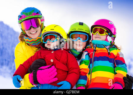 Madre e bambini Sciare in montagna. Active mamma e tre bambini con casco, occhiali e poli. Foto Stock