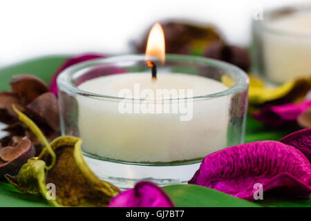 Composizione di candele accese fragrante potpourri sulla foglia di monstera Foto Stock