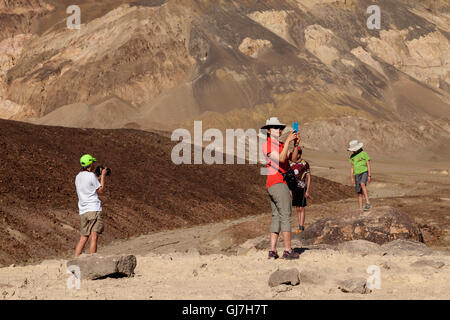 La donna a scattare foto di famiglia al vulcaniche e sedimentarie sulle colline vicino a artista della tavolozza in Parco nazionale della Valle della Morte, Calif Foto Stock