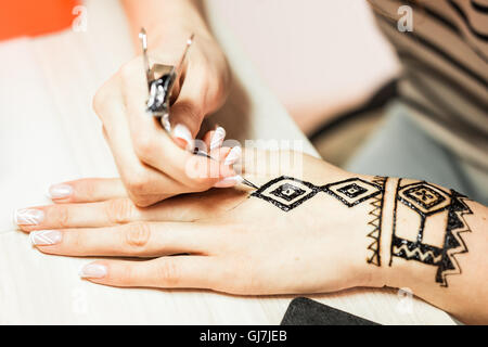 Processo di disegno di henna menhdi ornamento sulla donna di mano Foto Stock