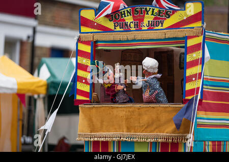 Signor Punch tenendo il bambino con Judy di fronte ad un punzone e Judy stand dei burattini Foto Stock