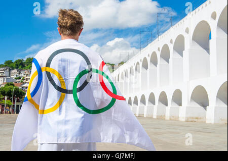 RIO DE JANEIRO - MARZO 06, 2015: atleta drappeggiati con bandiera olimpica si erge all'aperto nella plaza presso la famosa Lapa archi. Foto Stock