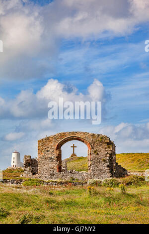 Le rovine di una chiesa di St Dwynwyn, guardando attraverso una finestra per una grande croce e il vecchio faro e Twr Mawr, sul tidal... Foto Stock