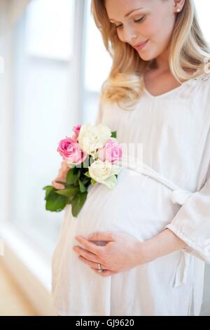 Modello rilasciato. Donna incinta holding posy di fiori. Foto Stock