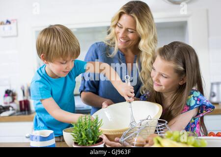 Proprietà rilasciato. Modello rilasciato. La madre e il figlio e la figlia cucina in cucina. Foto Stock