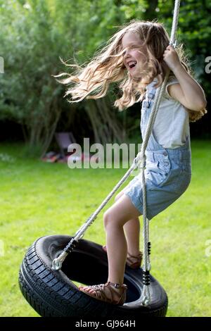 Proprietà rilasciato. Modello rilasciato. Ragazza che gioca su tyer swing. Foto Stock