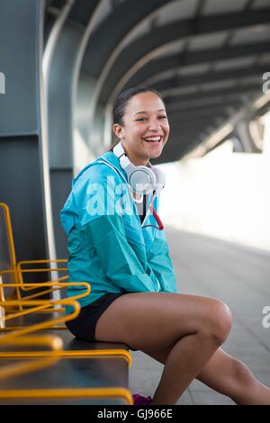 Modello rilasciato. Giovane donna seduta sulla piattaforma ferroviaria sorridente. Foto Stock