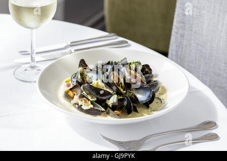 Cozze, moules mariniere servita su piastra bianca nel ristorante Foto Stock