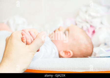 Tenere la mano neonato fasciatoio amore dei genitori Foto Stock
