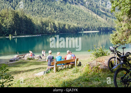 Un gruppo di appassionati di mountain bike di prendere un periodo di riposo su una panchina al bellissimo lago Vorderer Langbathsee in Austria, Salzkammergut Foto Stock