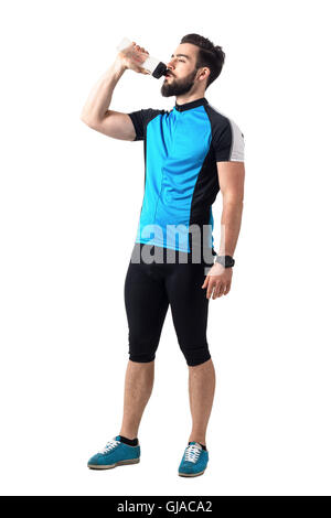 Esaurito atleta nel ciclismo sportivo di bere acqua da bottiglie di plastica. Corpo pieno lunghezza ritratto isolato su bianco Foto Stock