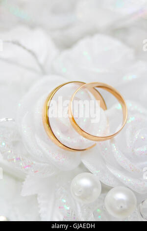Gli anelli di nozze giacente in fiori sintetici rose Foto Stock