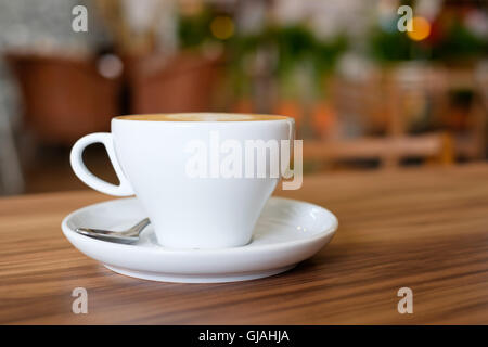 Un bianco mug tazza contenente caffè caldo sul tavolo di legno al cafe'. Foto Stock