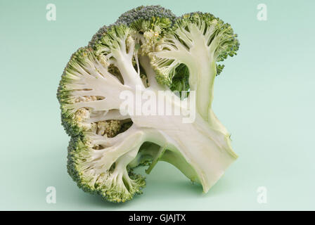 Broccoli freschi tagliati a metà su uno sfondo verde closeup. Foto Stock