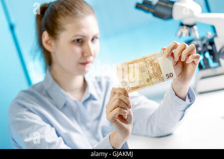 Donna verifica di autenticità di banconote in euro i soldi in un laboratorio Foto Stock