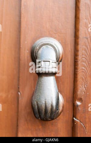 Vecchio nero a mano a forma di porta respingente sul marrone porta in legno closeup. Kato Drys. Cipro. Foto Stock