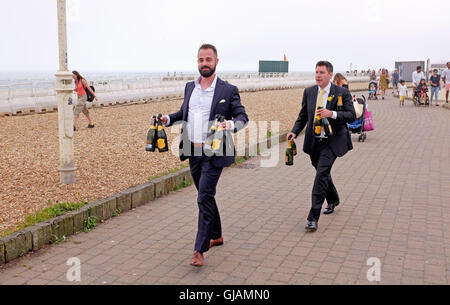 Gli ospiti dei matrimoni al bandstand Brighton Seafront trasportare bottiglie di Prosecco spumante Foto Stock