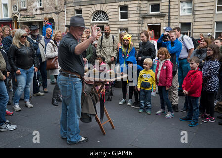 Un prestigiatore intrattenere i visitatori al Edinburgh Fringe Festival sul Royal Mile. Foto Stock