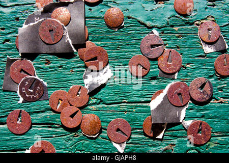 Il marcio thumbtacks sul verde rigato tagliere in legno con pezzi strappati di vecchi annunci e notizie Foto Stock