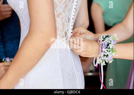 Damigella sta aiutando la sposa di vestire Foto Stock