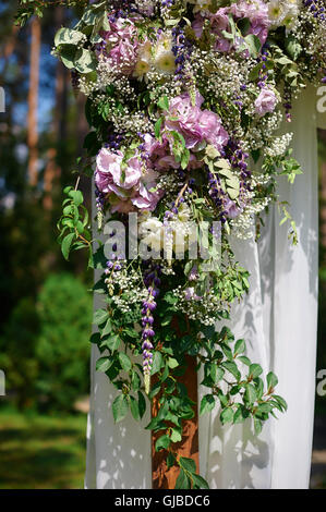 Arco di nozze decorato con fiori di vetro e vasi appesi Foto Stock