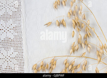 Avena Grani di cereali fatti a mano sulla tovaglia di lino con pizzo. Close-up Foto Stock